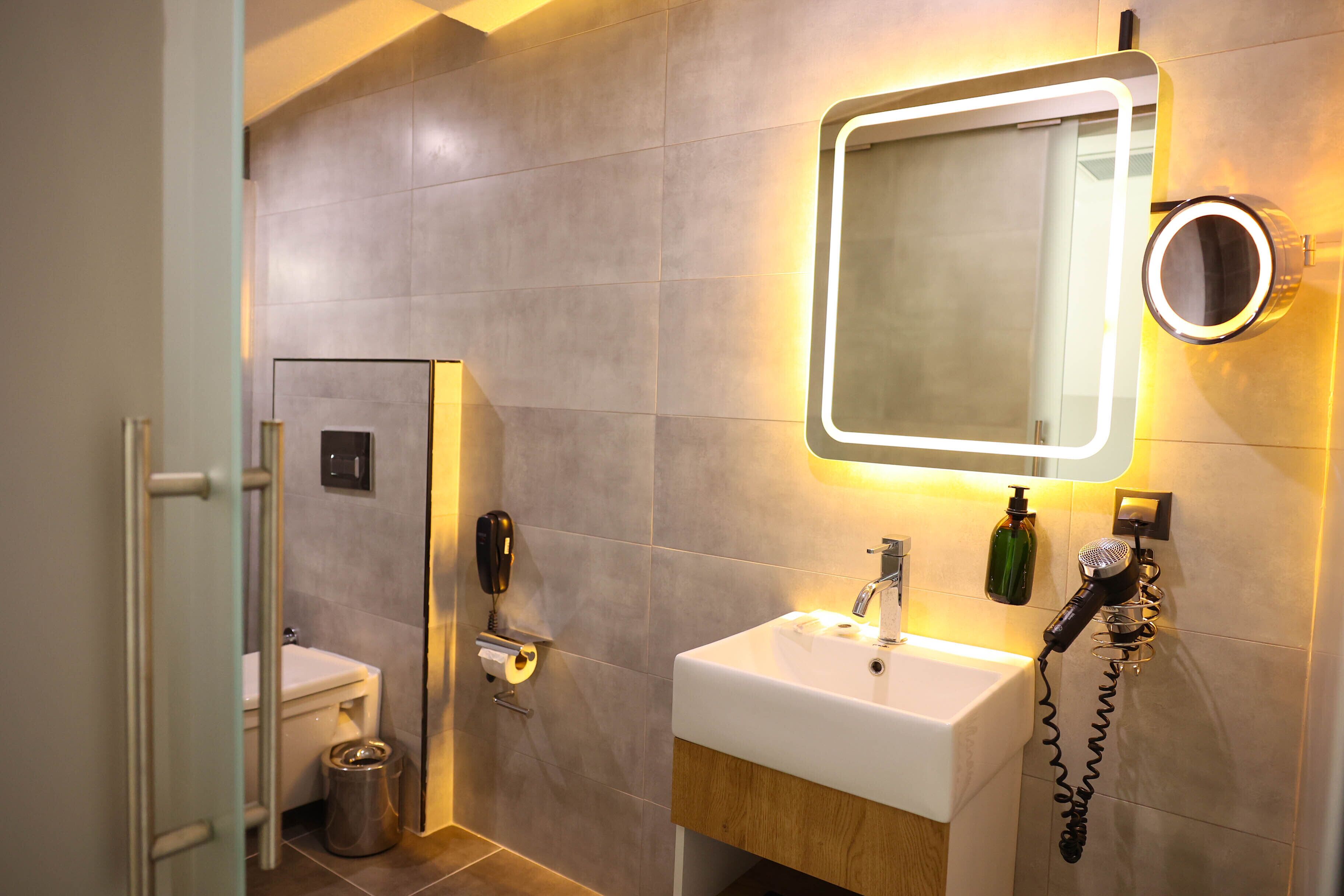 A modern bathroom with a large mirror, a sink, and a toilet.