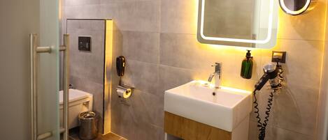 A modern bathroom with a large mirror, a sink, and a toilet.