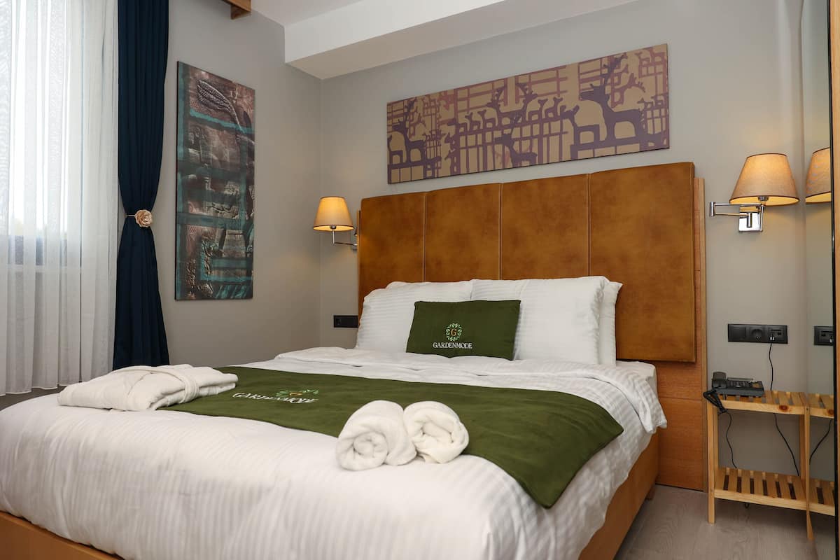 Una cama cuidadosamente tendida con una toalla verde y una almohada con la etiqueta 'Garden Mode'.