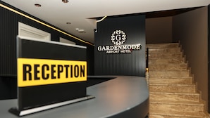 A reception desk with a sign reading "RECEPTION" and a staircase leading to an upper level. - Garden Mode Airport Hotel (Arnavutköy)