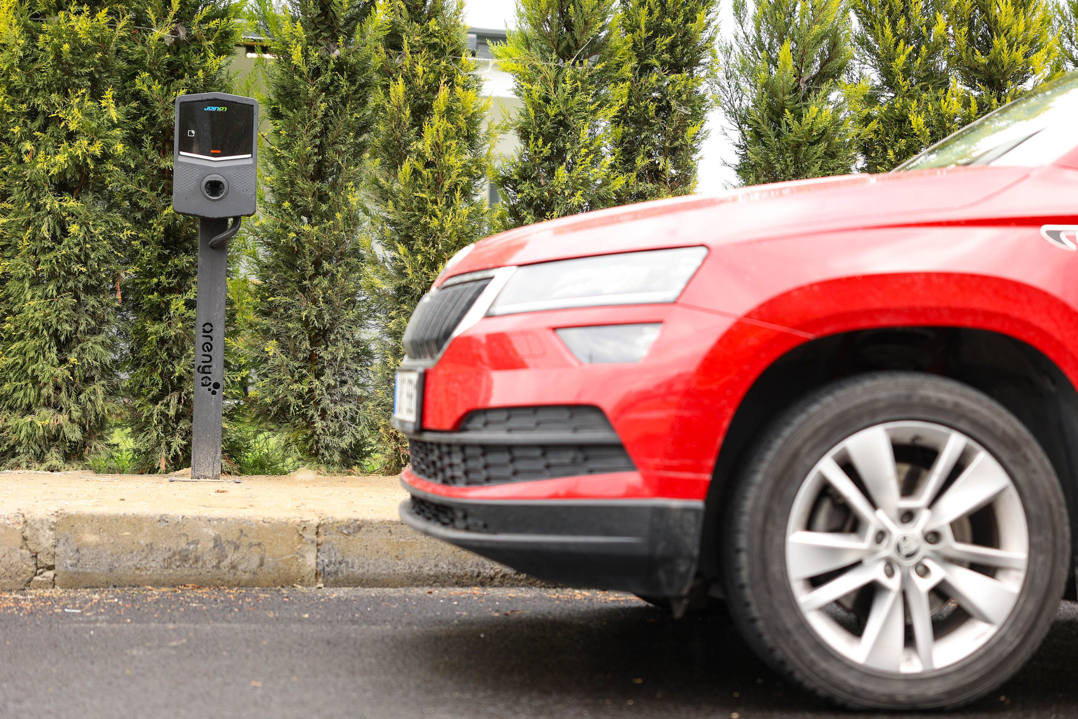 A red car parked next to a charging station.