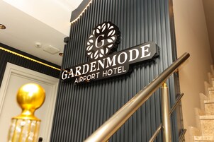 Señal del Hotel Gardenmode Airport, con un diseño moderno y una escalera.