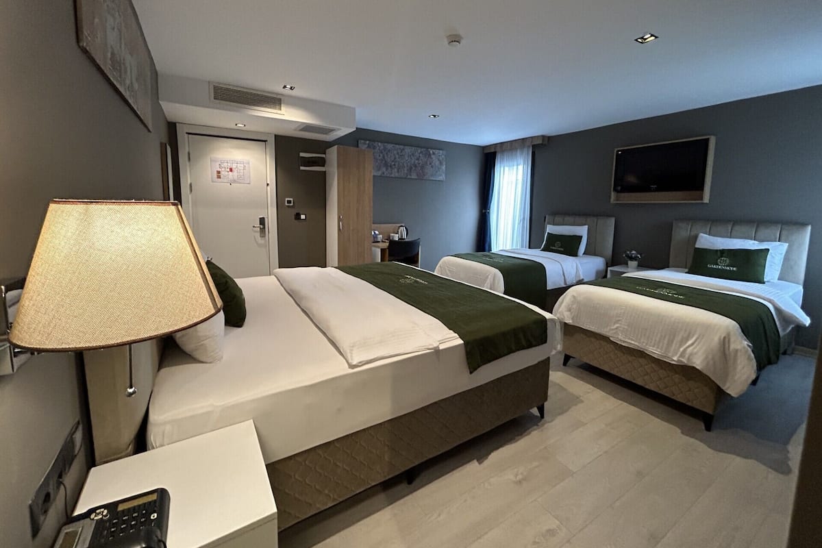 Habitación de hotel con dos camas, un escritorio, una lámpara y un televisor.