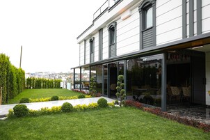 Un edificio moderno con un jardín bien cuidado, grandes ventanales y vistas a la ciudad.