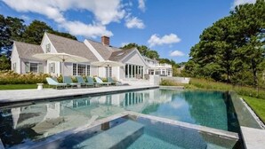 A large house with a swimming pool and outdoor seating. - The Ultimate Cape Cod luxury home. Dock, pool, hot tub and views! RPMS104 (Osterville)