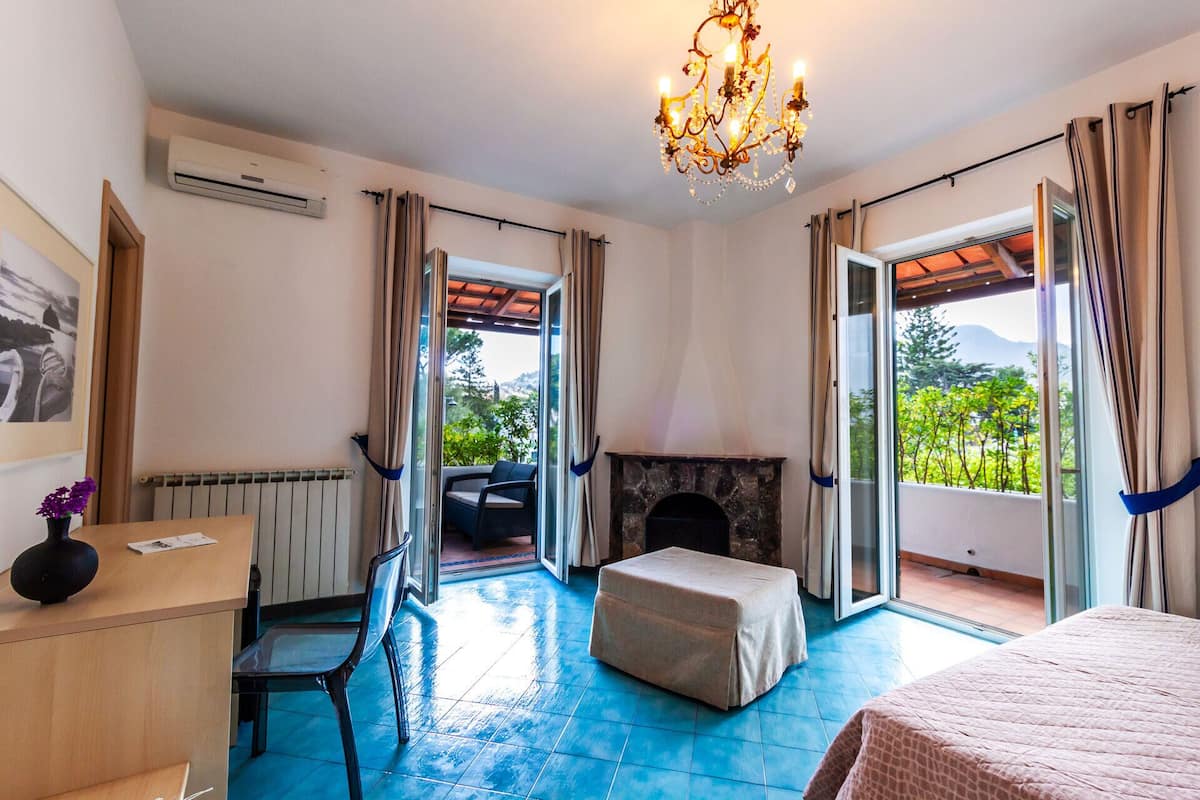 A bedroom with a fireplace, a desk, a chair, and a bed.