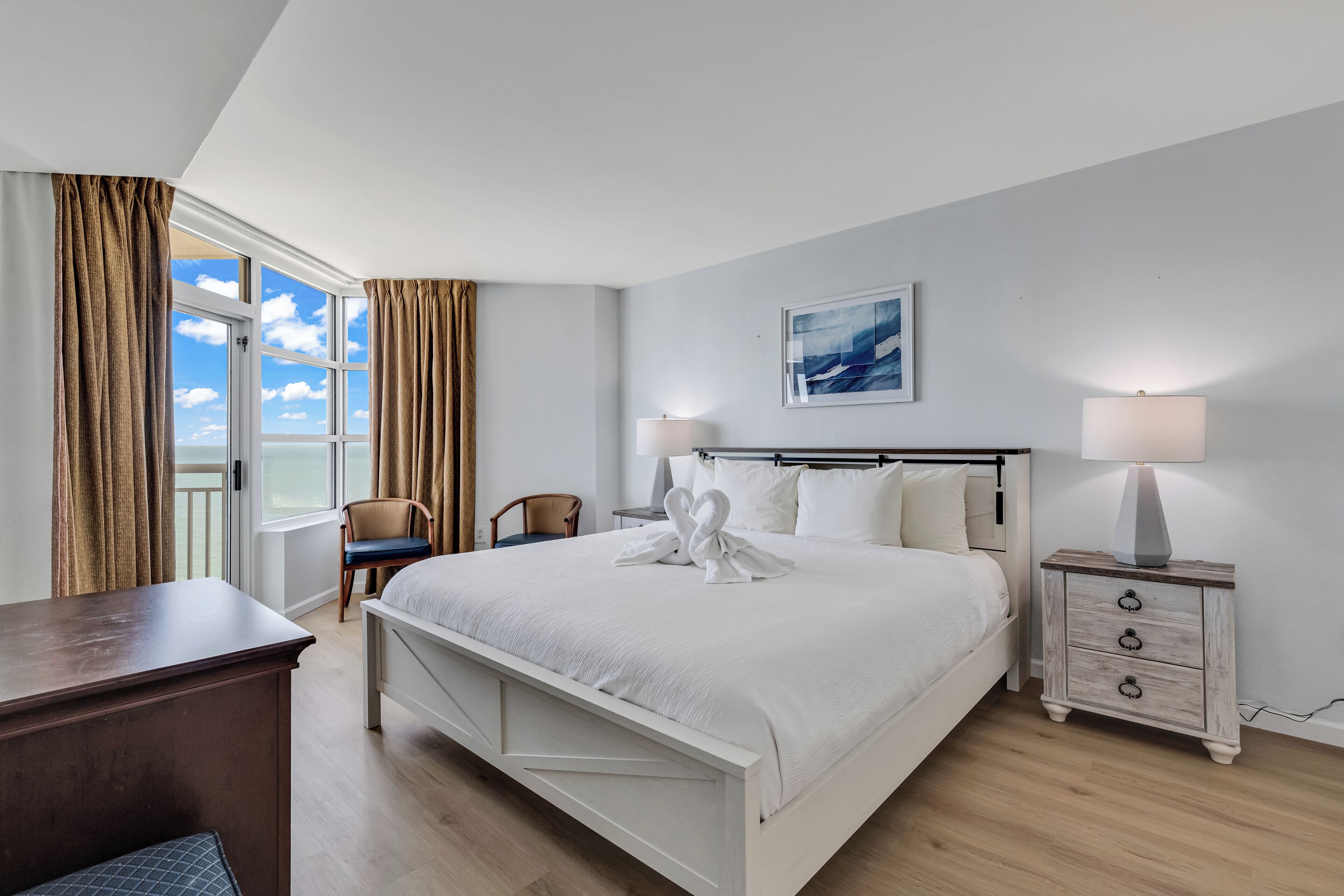 A hotel room with a large bed, two bedside tables, a desk, and a chair.