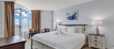 A hotel room with a large bed, two bedside tables, a desk, and a chair.