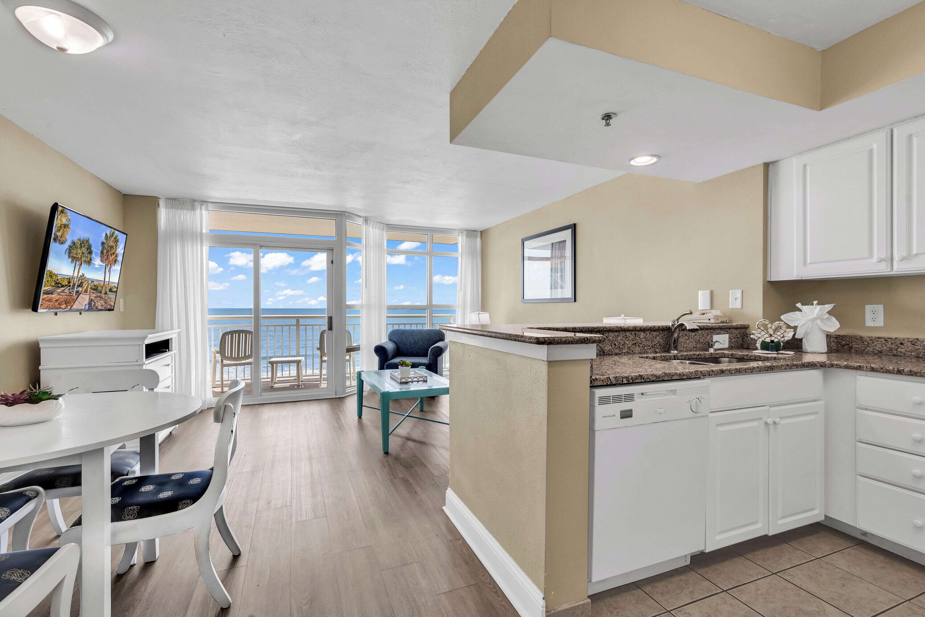A modern kitchen with white cabinets, a granite countertop, and a built-in dishwasher.
