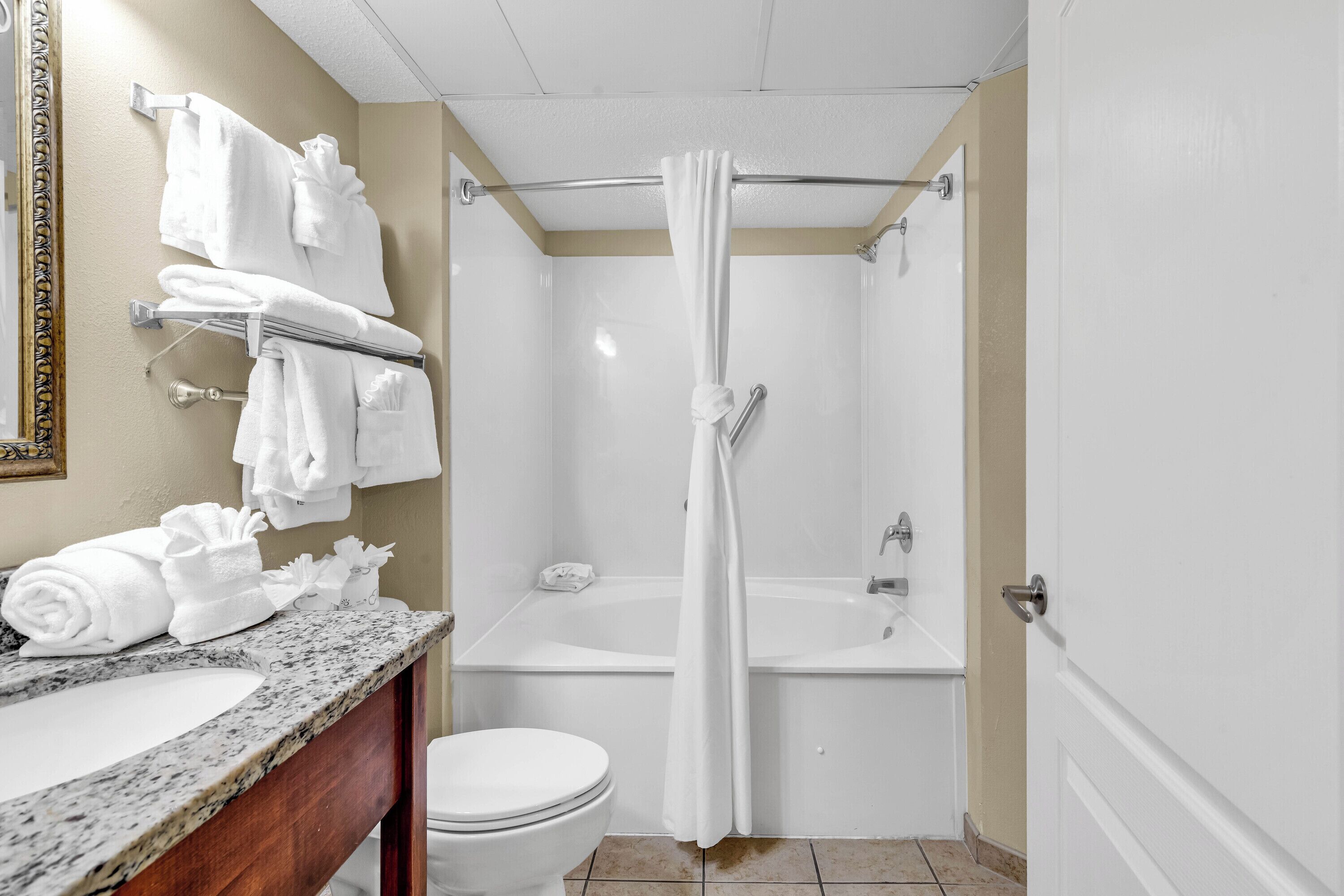 Ein Badezimmer mit Marmorwaschbecken, weißer Toilette und Duschbereich mit Vorhang.