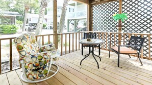 Eine Holzterrasse mit einem Schaukelstuhl, einem Tisch und zwei Stühlen.