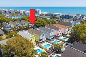 Un quartier résidentiel avec des maisons, une piscine et une vue sur l’océan.