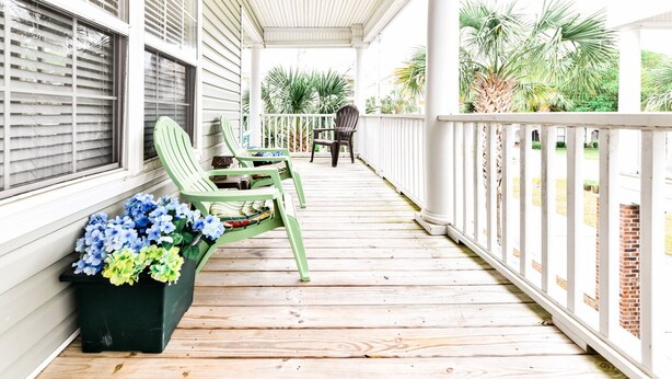 A covered porch with wooden flooring, white railings, and green chairs. - Walk to the Beach 5 BR Beach House with a Private Pool! Catching R.A.E.S (Surfside Beach)