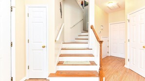 A staircase with wooden steps and white walls, leading to a landing with a door. - Walk to the Beach 5 BR Beach House with a Private Pool! Catching R.A.E.S (Surfside Beach)
