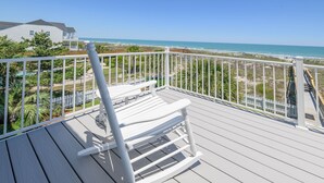 A wooden deck with a rocking chair, white railings, and a view of the beach and ocean. - Oceanfront 7 BR Beach House with a Private Pool! Crown Jewel  (Garden City)