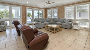 A spacious living room with a leather sofa, a grey sectional, and a coffee table. - Oceanfront 7 BR Beach House with a Private Pool! Crown Jewel  (Garden City)