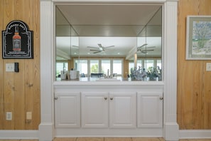 A kitchen with a large window, wooden paneling, and a ceiling fan.