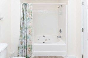 Bathroom features a bathtub, toilet, and shower curtain with a floral pattern.