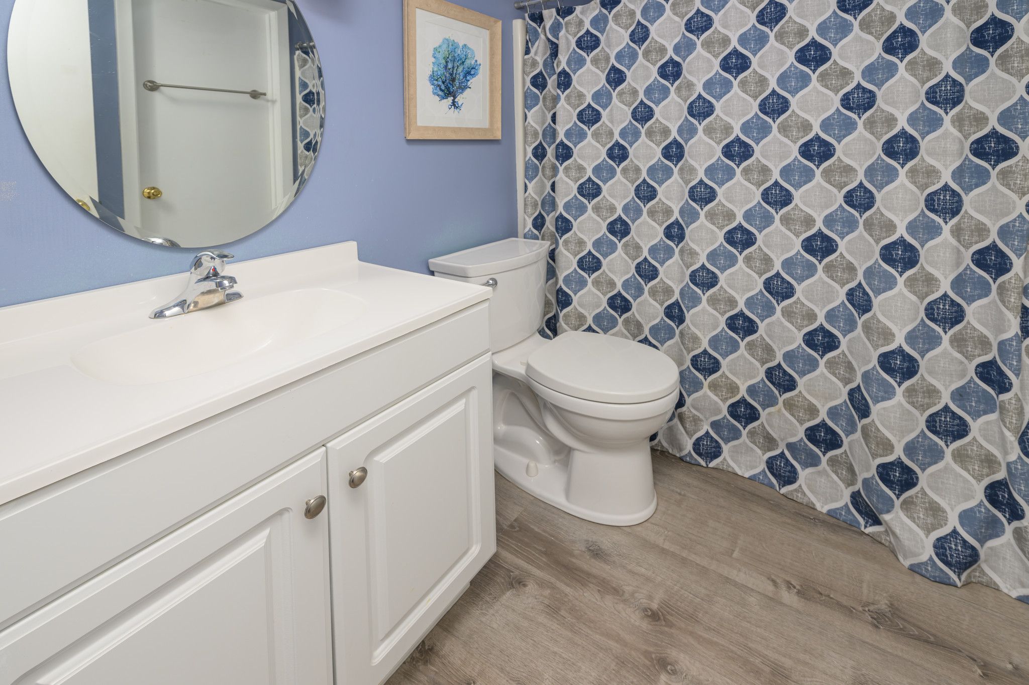 A bathroom with a white sink, a toilet, and a shower curtain with a geometric pattern.