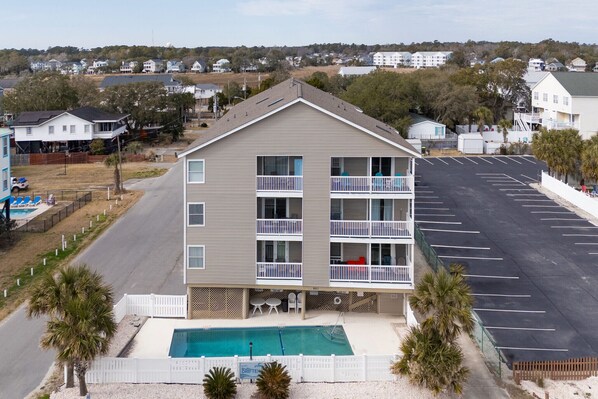 A multi-story hotel with a pool, balconies, and a parking lot.