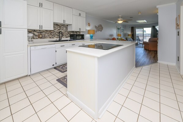 A modern kitchen with white cabinets, a central island, and a microwave.