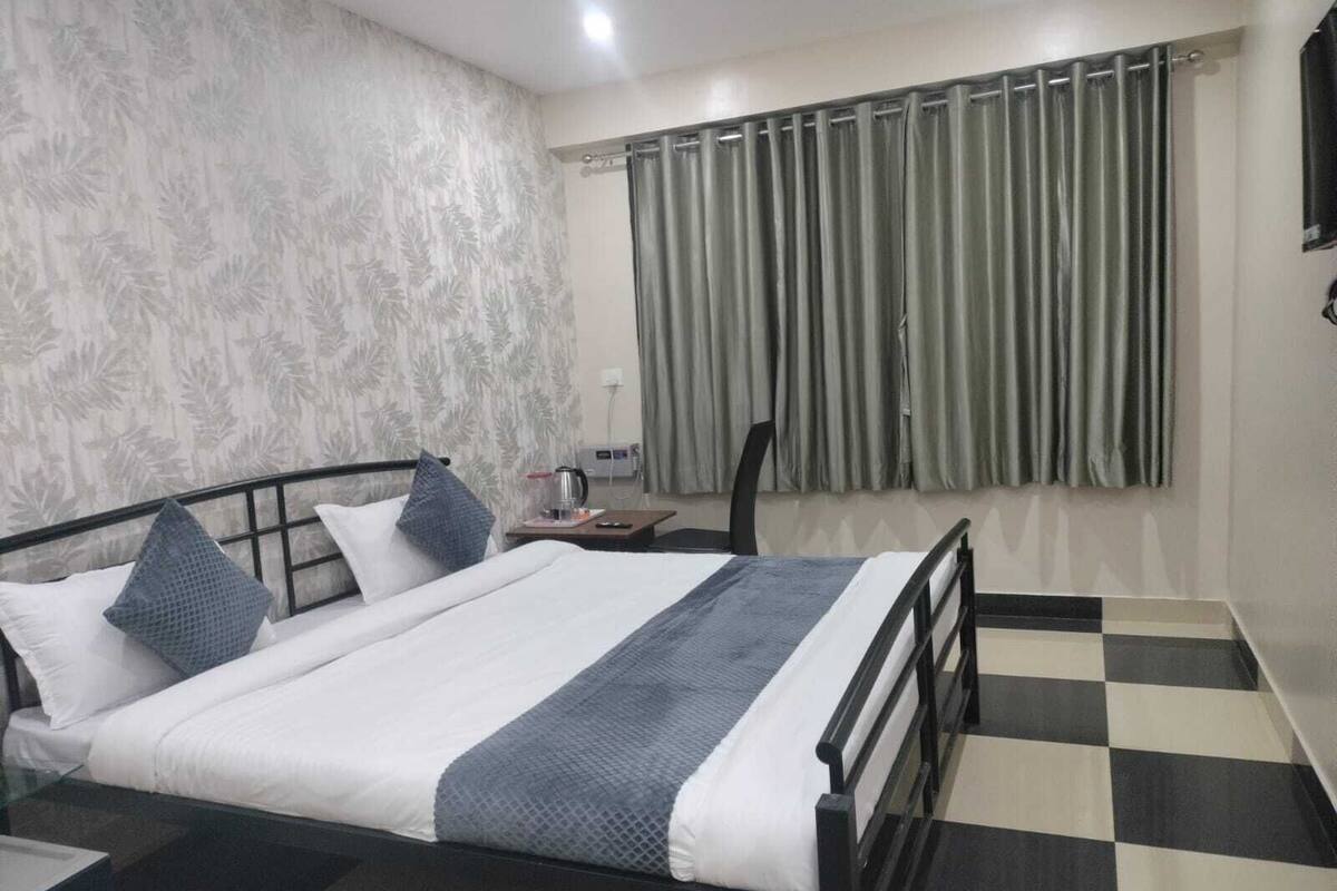 A neatly arranged bedroom with a bed, a nightstand, a chair, and a window with curtains.