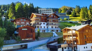 A modern ski resort with wooden buildings, a ski lift, and a mountain backdrop.