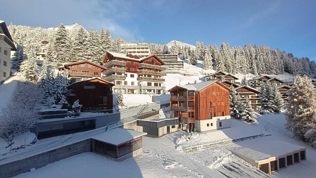 A snow-covered mountain resort with wooden buildings and ski slopes.
