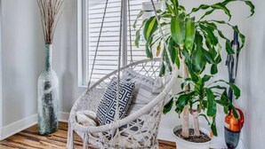 A room with a white wicker chair, a large green plant, and a tall vase with branches. - Sea house @ Sea shore - 4 bedroom, 3 bath - 14 ppl (San Diego)