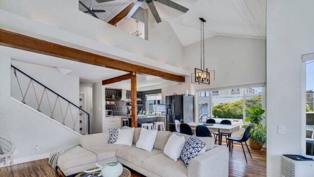 A spacious living area with a large sectional sofa, wooden flooring, and a staircase with a geometric railing. - Sea house @ Sea shore - 4 bedroom, 3 bath - 14 ppl (San Diego)
