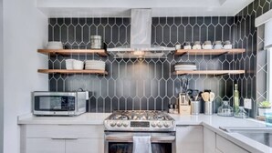 A modern kitchen with a gas stove, oven, microwave, and wooden shelves above. - Sea house @ Sea shore - 4 bedroom, 3 bath - 14 ppl (San Diego)