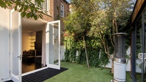 Un bâtiment moderne doté d’une porte en verre qui donne sur une pièce contenant un canapé et une table.