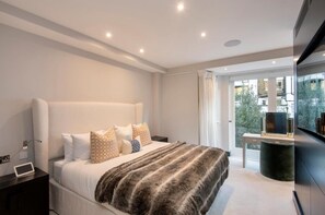 A modern bedroom with a large bed, bedside tables, a TV, and a view of the outside. - Stunning 5-bed House in London (London)