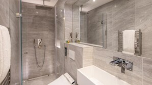 Une salle de bain moderne avec une douche à parois de verre, un grand miroir et des toilettes intégrées.