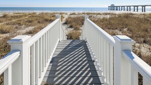 A wooden boardwalk leading to a beach with a pier in the background. - Oceanfront 5 BR Beach House with a Private Pool! Sea Salt (Surfside Beach)