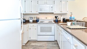 Una cocina moderna con armarios blancos, estufa de acero inoxidable y microondas integrado.
