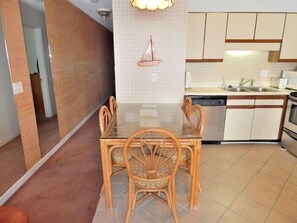 A modern kitchen with a glass dining table and wicker chairs, a dishwasher, and a stove.