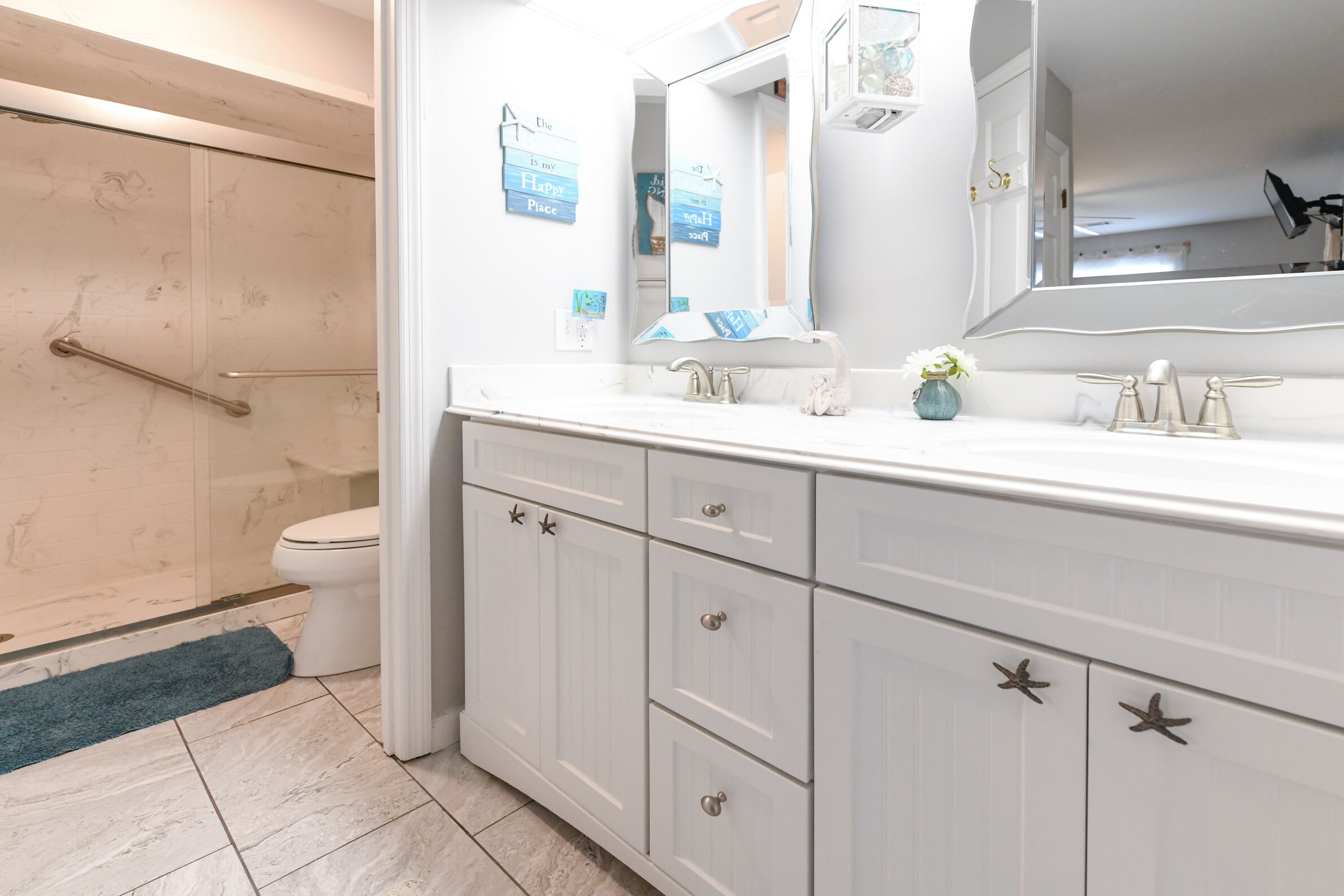 A bathroom with a white vanity, a large mirror, and a shower area with a handrail.