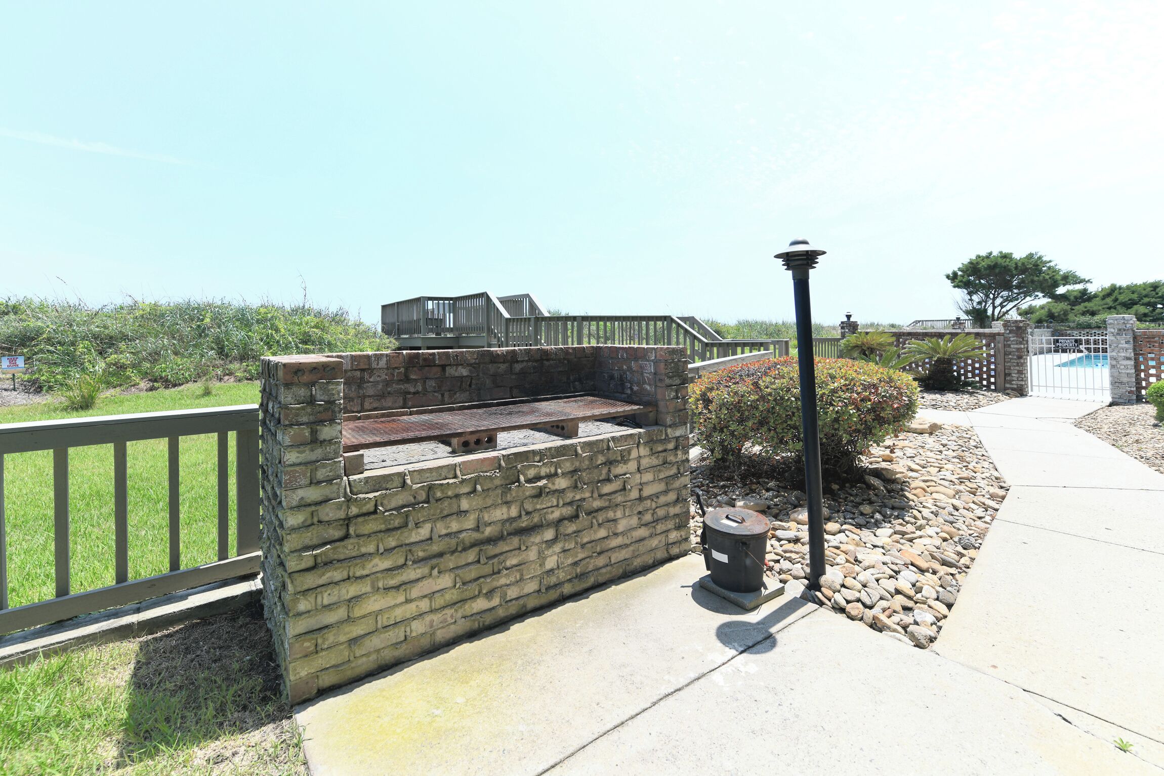 Un barbecue en pierre avec un toit en métal, une poubelle et un lampadaire.