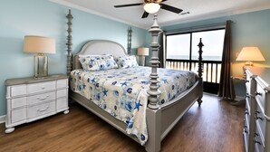 Une chambre à coucher comprenant un lit, une table de chevet, une commode, un ventilateur de plafond et une fenêtre donnant sur un paysage agréable.