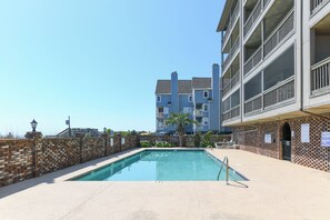 Una piscina con un muro de ladrillo y un edificio al fondo.