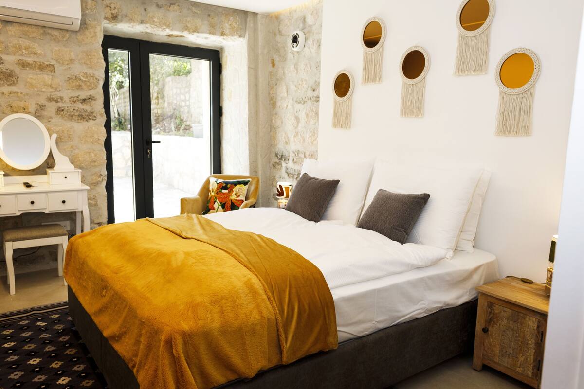 A bedroom with a bed, a dresser, a mirror, and macramé wall decorations.