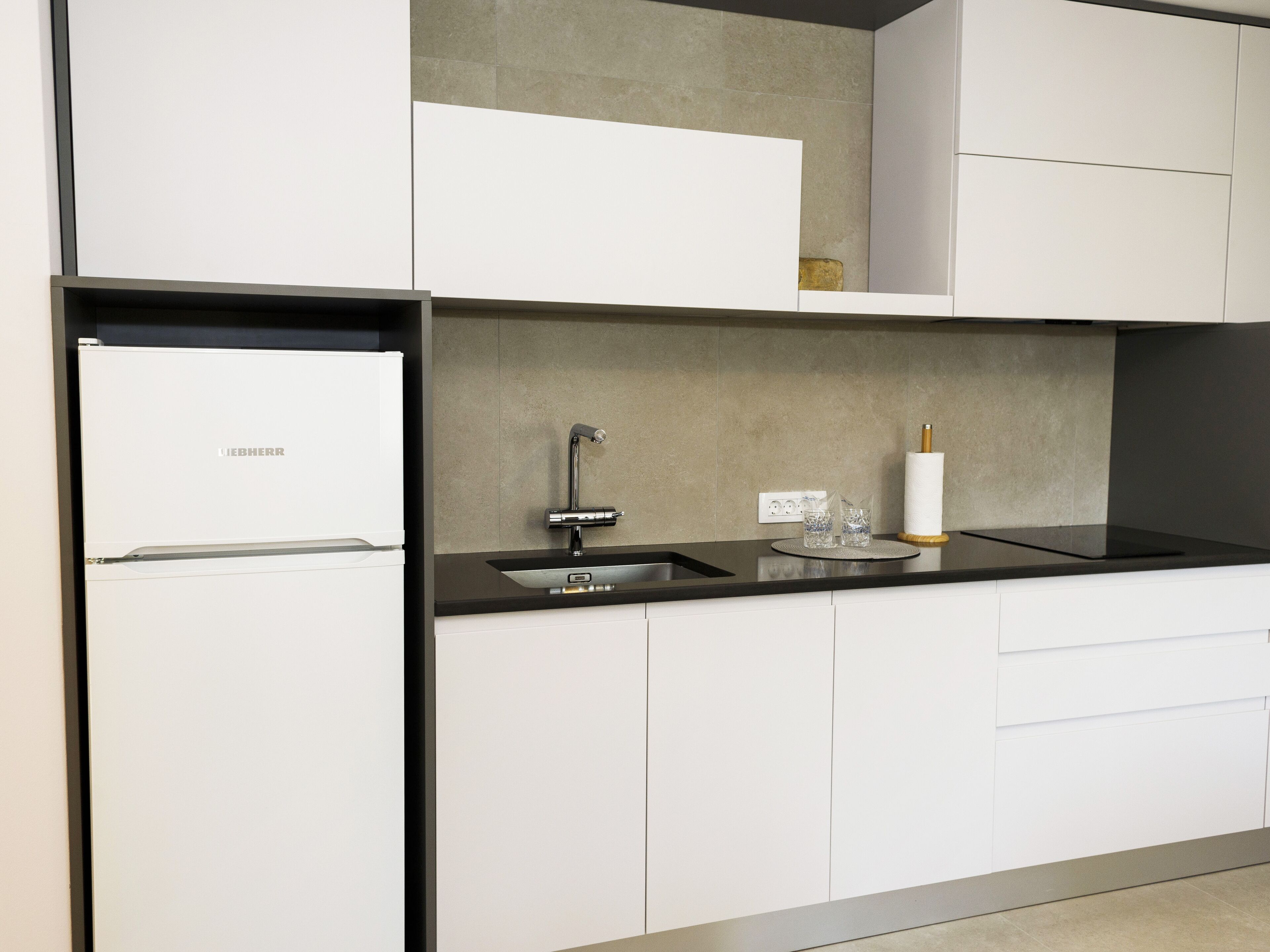 Een moderne keuken met witte kastjes, een zwart aanrecht en een roestvrijstalen spoelbak.