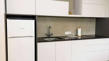 Een moderne keuken met witte kastjes, een zwart aanrecht en een roestvrijstalen spoelbak.