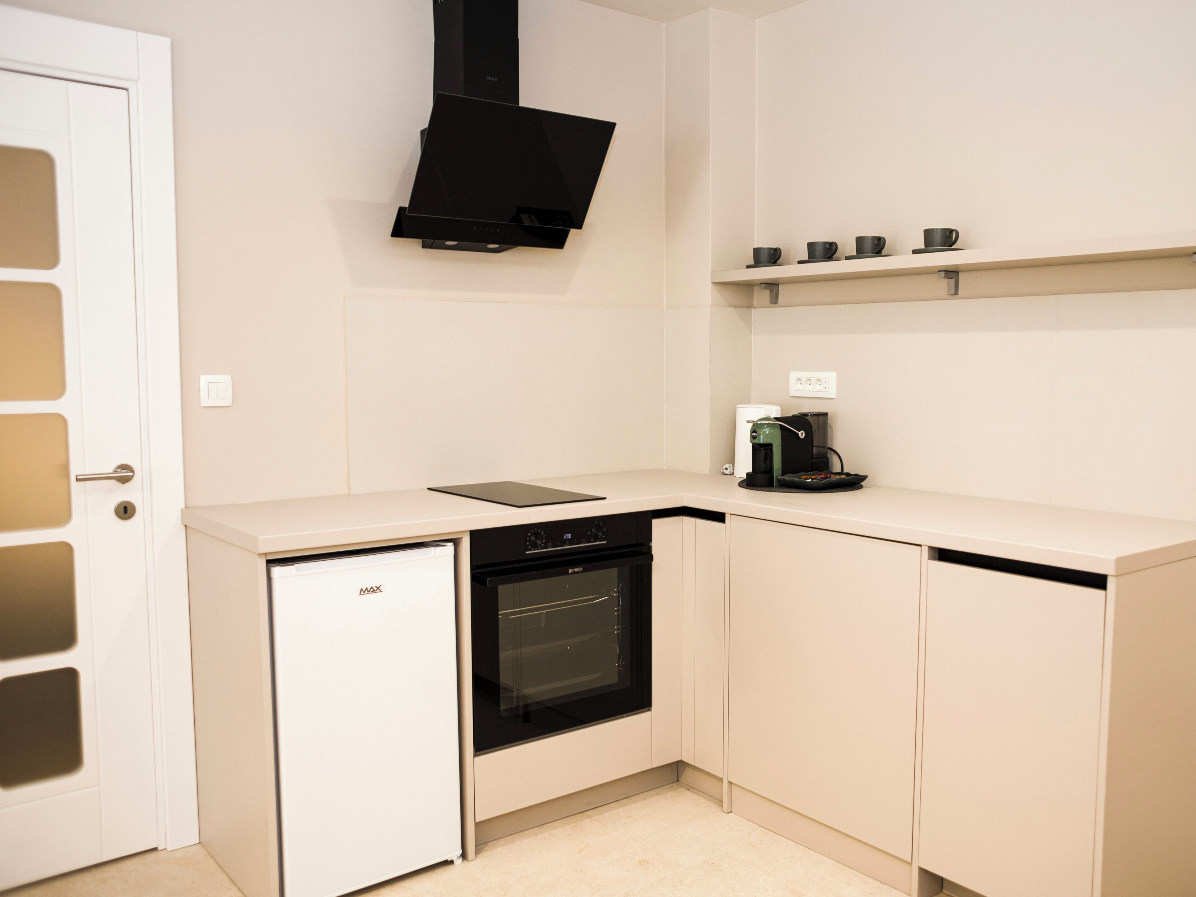 A compact kitchen with a dishwasher, oven, and a coffee maker on the countertop.