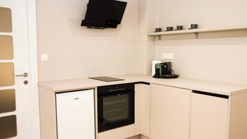 A compact kitchen with a dishwasher, oven, and a coffee maker on the countertop.