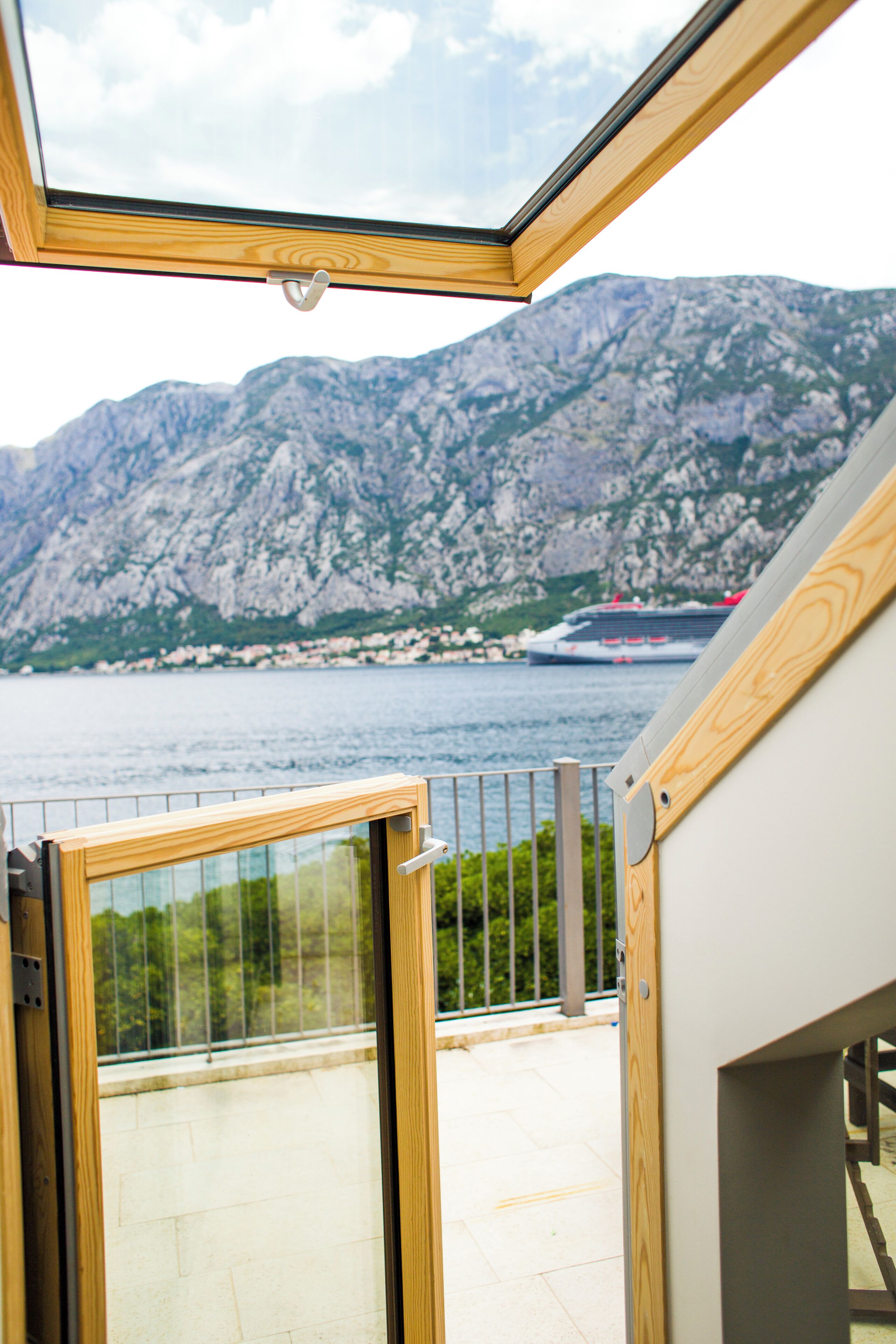 A balcony with a view of a mountain and a cruise ship in the distance.