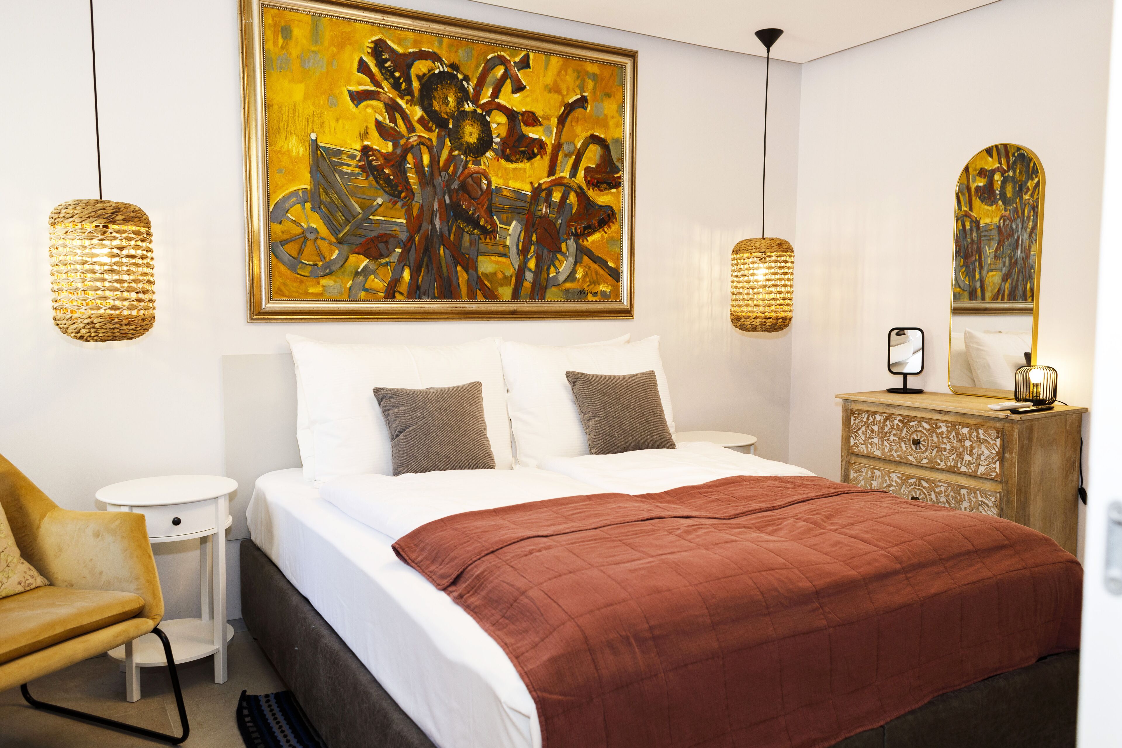 Un dormitorio moderno con una cama grande, una mesita de noche, una silla, un aparador y dos lámparas de pared.