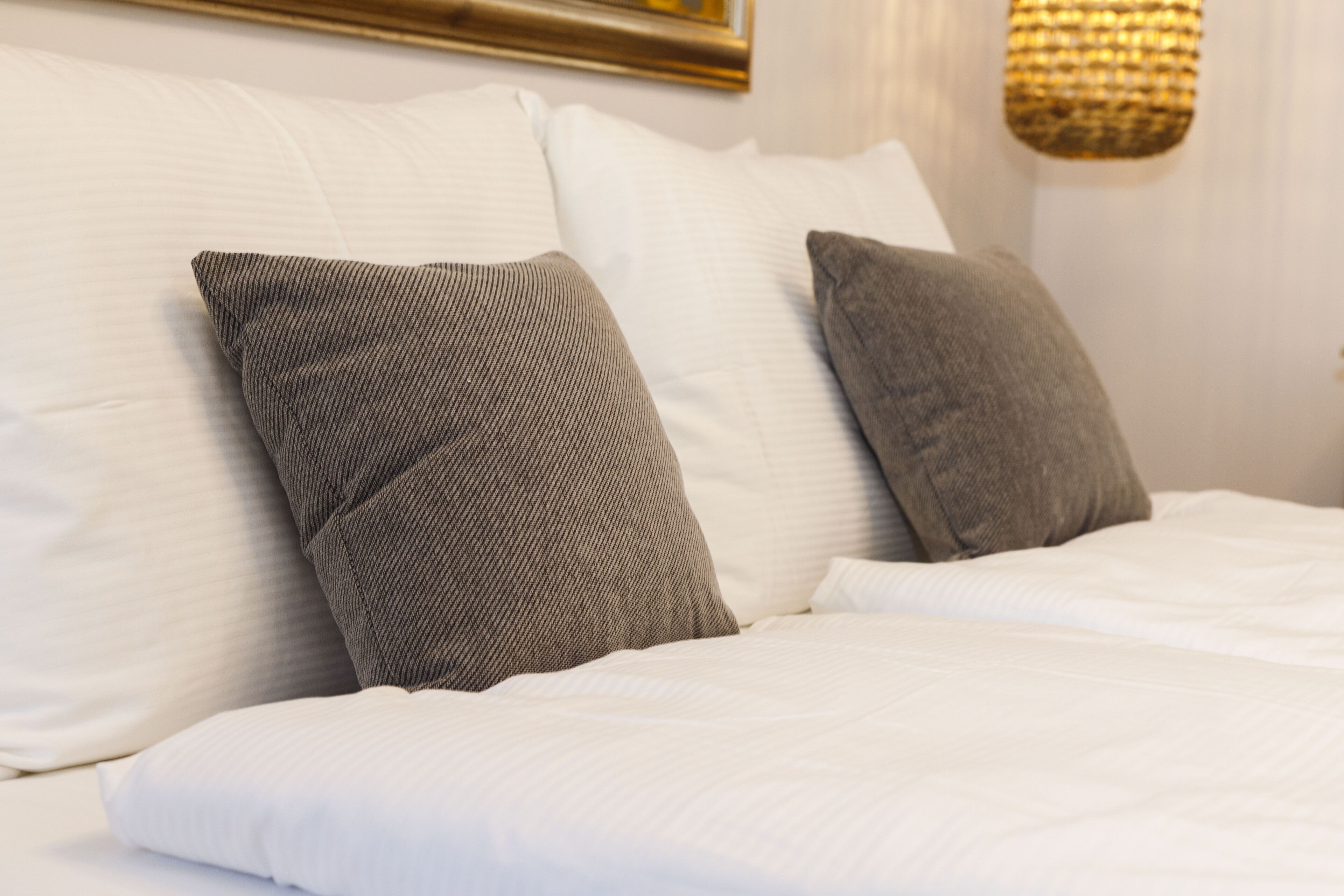 A neatly made bed with white bedding and two gray pillows.