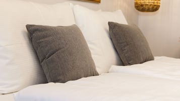 A neatly made bed with white bedding and two gray pillows.